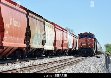 Naperville, Illinois, USA. Canadian National Railway locomotives lead a  freight train paused on a siding while being passed by another freight train. Stock Photo