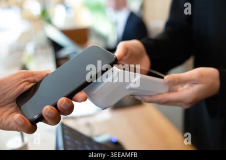 Customer making contactless payment with smartphone, closeup Stock Photo