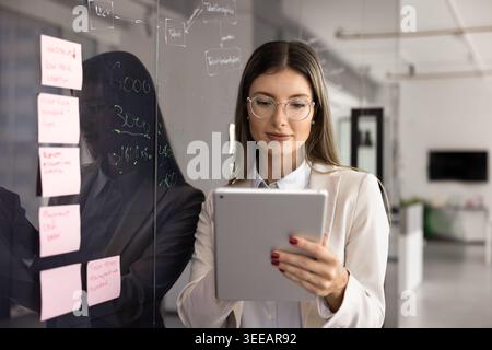 Focused businesswoman working on digital tablet device Stock Photo