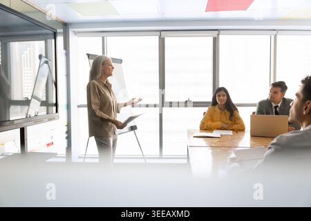 Middle-age businesswoman explaining business strategy to team during meeting Stock Photo