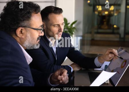 Two businessmen reviewing business report on laptop Stock Photo
