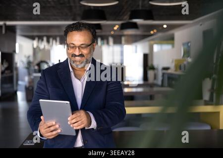 Middle-age businessman working on digital tablet in coworking office Stock Photo