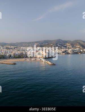 Aerial view of the Church of Sant Bartomeu i Santa Tecla overlooking the Mediterranean Sea, sandy beaches, and white coastal buildings in Sitges, Cata Stock Photo