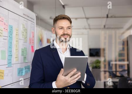 Thoughtful businessman holding digital tablet in workplace Stock Photo