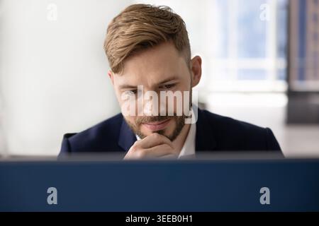 Man looking at computer screen with thoughtful expression Stock Photo