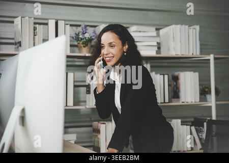 Confident female trader analyzing financial charts on multiple monitors in home office Stock Photo