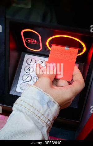 Woman's hand inserting a credit card into a bank ATM to withdraw money. Stock Photo