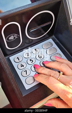 Woman's hand dialing numbers on a keyboard of a bank teller to withdraw money. Stock Photo