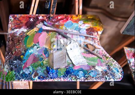 Palette with artists brushes and oil paints on wooden easel Stock Photo