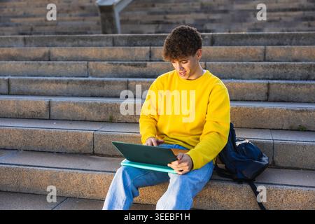 College student studying on laptop outdoors on steps Stock Photo