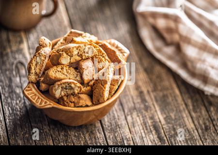 Warm almond biscotti cantuccini piled in a ceramic bowl beside a coffee cup on a rustic wooden table, evoking cozy morning vibes, homemade baking, and a comforting breakfast or snack moment. Stock Photo