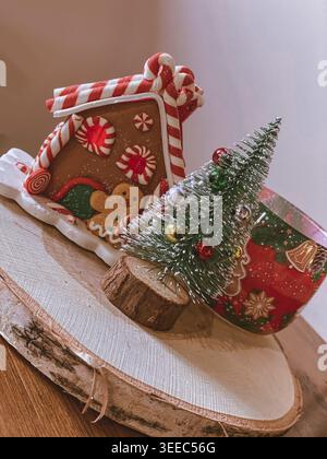 Gingerbread house decoration with mini Christmas tree on wooden board, cozy festive scene Stock Photo