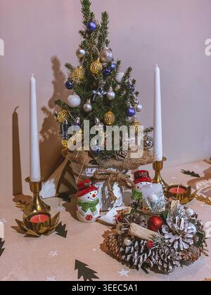 Decorated Christmas tree with candles on table, cozy indoor festive holiday composition Stock Photo