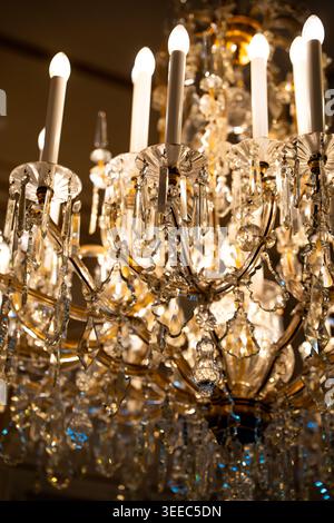 Close up of a crystal chandelier with electrical lights against a dimly lit dark background for luxury interior and lighting concept Stock Photo