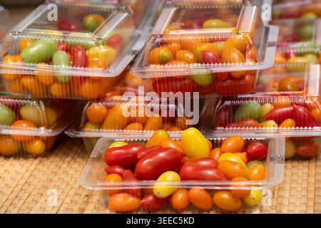Assorted colorful grape tomatoes in transparent plastic containers for sale at a local market. Stock Photo