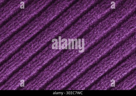 Close up, macro of purple colored knitted fabric with diagonal relief ribbed pattern and soft wool texture. Detailed textile surface, knitwear backgro Stock Photo