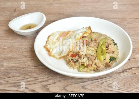 spicy fried mixed rice with chop pork basil topping egg in plate dipping chili fish sauce Stock Photo