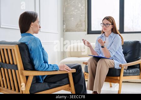Young woman during consultation with female life coach or psychologist in modern office Stock Photo