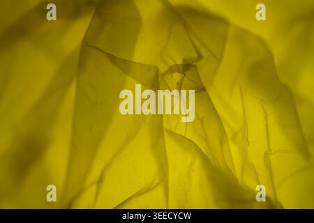 Extreme close up of yellow plastic texture background. The plastic surface is wrinkly and tattered making abstract pattern. Selective focus, shallow d Stock Photo