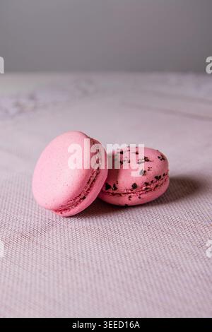 two pink french macaroons with sprinkles on a light textile background Stock Photo