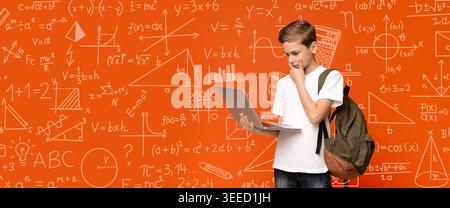 Student Using Laptop in Front of Math and Science Equations on a Wall as Part of a Study Session Stock Photo