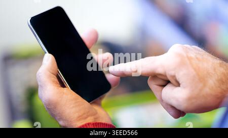 Hand Holding Smartphone With Finger Touching Screen in a Store Setting During Daylight Hours Stock Photo