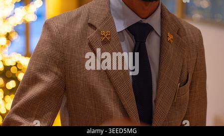 A close-up shot of a hotel concierge wearing suit jacket, featuring the prestigious gold crossed keys pin . Stock Photo