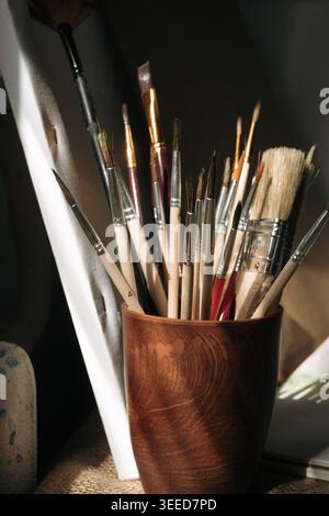 Close up of pottery cup with painting brushes in studio of artist. Creativity concept Stock Photo