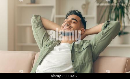Man Relaxes on Sofa While Listening to Music in a Bright Room During the Day Stock Photo