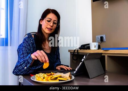 Woman working remotely during breakfast morning routine Stock Photo