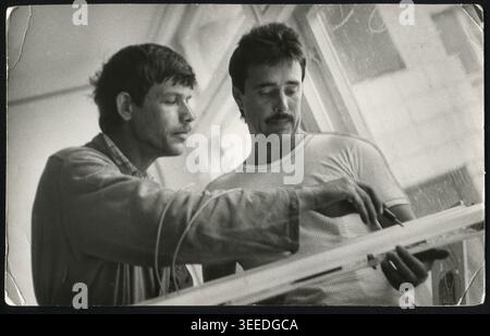 Two young engineers discussing technical drawings in a design office during the 1970s. Authentic Soviet photograph. Stock Photo