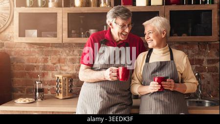 Cheerful seniors drinking morning coffee and talking at kitchen Stock Photo