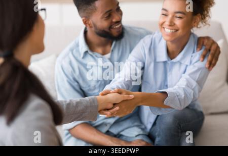 Cheerful african american spouses and psychologist handshaking in office Stock Photo