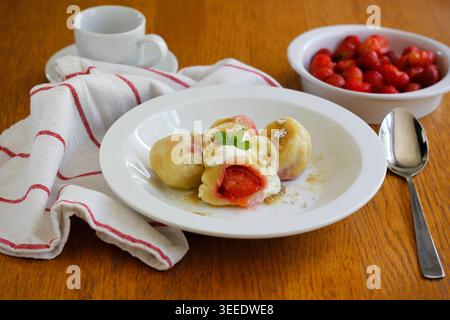 Homemade strawberry dumplings made from quark dough, served with powdered cane sugar and quark, traditional summer dessert popular in Czechia Stock Photo