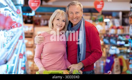Couple Shopping Together in Grocery Store With Shopping Cart Full of Fresh Produce Stock Photo