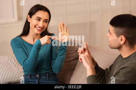 Couple Sitting On Sofa Communicating With Sign Language Stock Photo