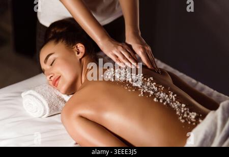 Woman Enjoying Salt Scrub Massage, Relaxing In Health Spa Stock Photo