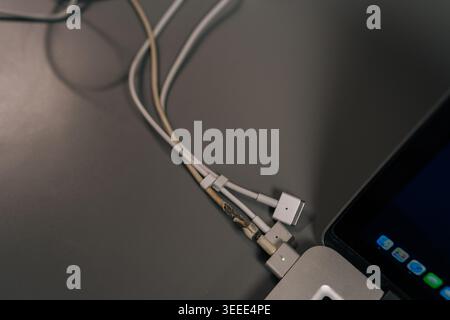 Damaged laptop charger cable with exposed wires showing wear and tear, representing electronic failure, potential hazard, and the need for repair or r Stock Photo