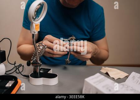 Cropped shot of technician male working on electronics using a soldering iron and a magnifying lamp, carefully assembling or repairing a circuit board Stock Photo