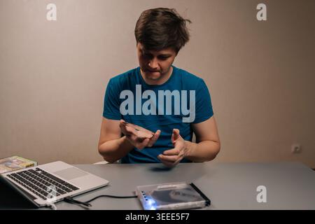 Portrait of man connecting external usb dvd drive to a modern laptop, transferring or accessing data from a cd dvd for backup, media playback, or file Stock Photo