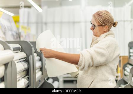 Woman choosing wallpaper sample in home improvement and decor store Stock Photo