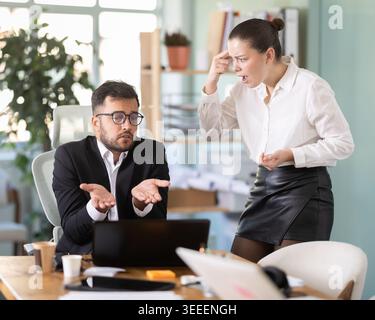female boss stands in the office and scolds on a male IT department employee Stock Photo