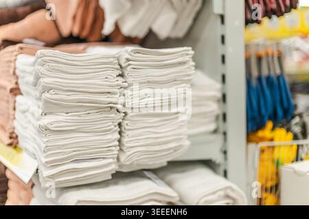 Stacks of folded white towels displayed on retail shelf in home goods store Stock Photo