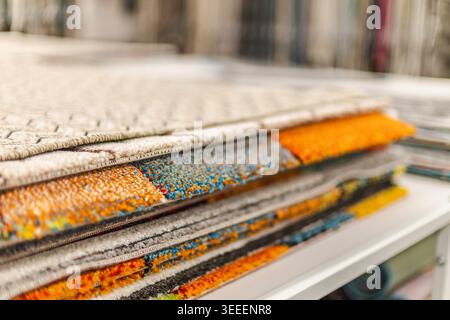 Stack of colorful carpet samples and decorative rugs in home improvement store Stock Photo