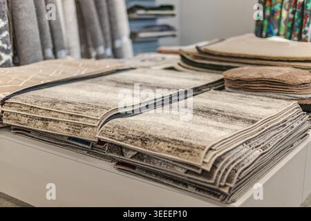 Folded carpet and rug samples displayed on table in home improvement store Stock Photo