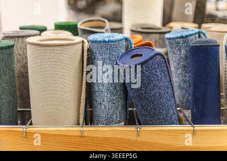 Rolled carpet samples and colorful floor mats displayed in home improvement store Stock Photo