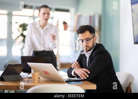 female boss stands in the office and scolds on a male IT department employee Stock Photo