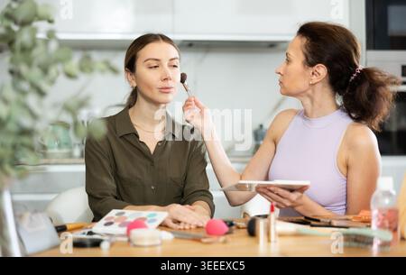 Female makeup artist brushing blush onto woman face Stock Photo