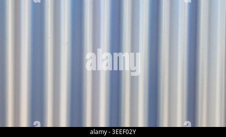 Close up photograph features corrugated metal with silver and blue tones. Lighting highlights linear texture, for industrial, construction, or minimal Stock Photo