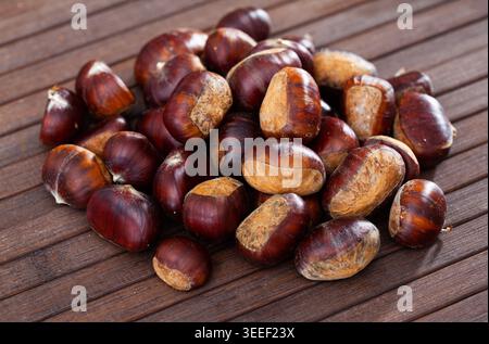 Unpeeled edible sweet chestnuts on wooden background Stock Photo